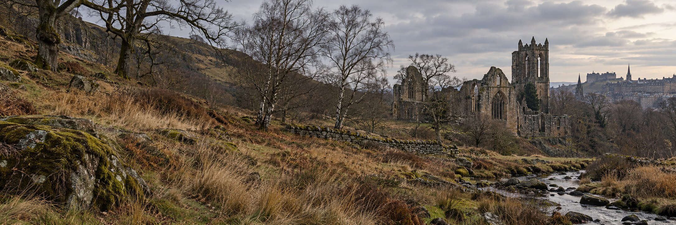 A burn running past an abbey ruin below the hills, the city skyline beyond